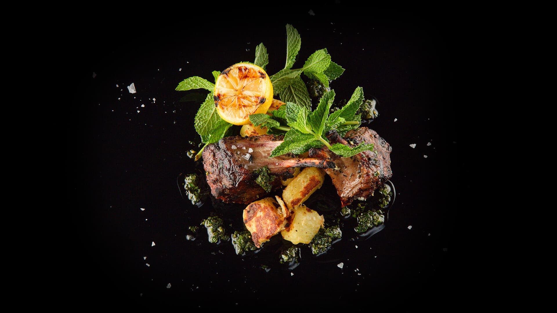 Wood-fired lamb with mint and charred lemon at Monzú, plated on black